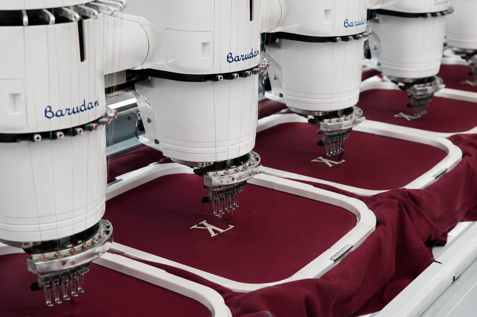 Barudan Japanese embroidery machines stitching monogram on maroon uniform fabric