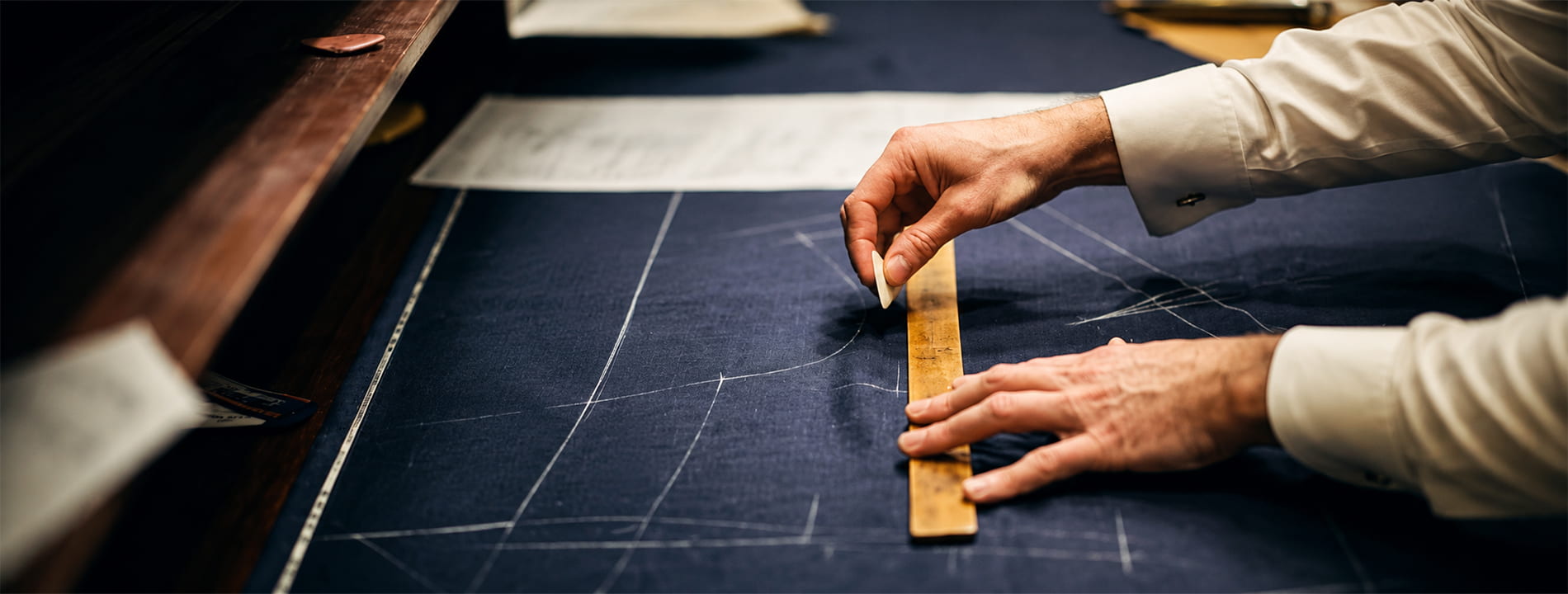 Tailor chalk-marking fabric during uniform pattern making at Sona Signature